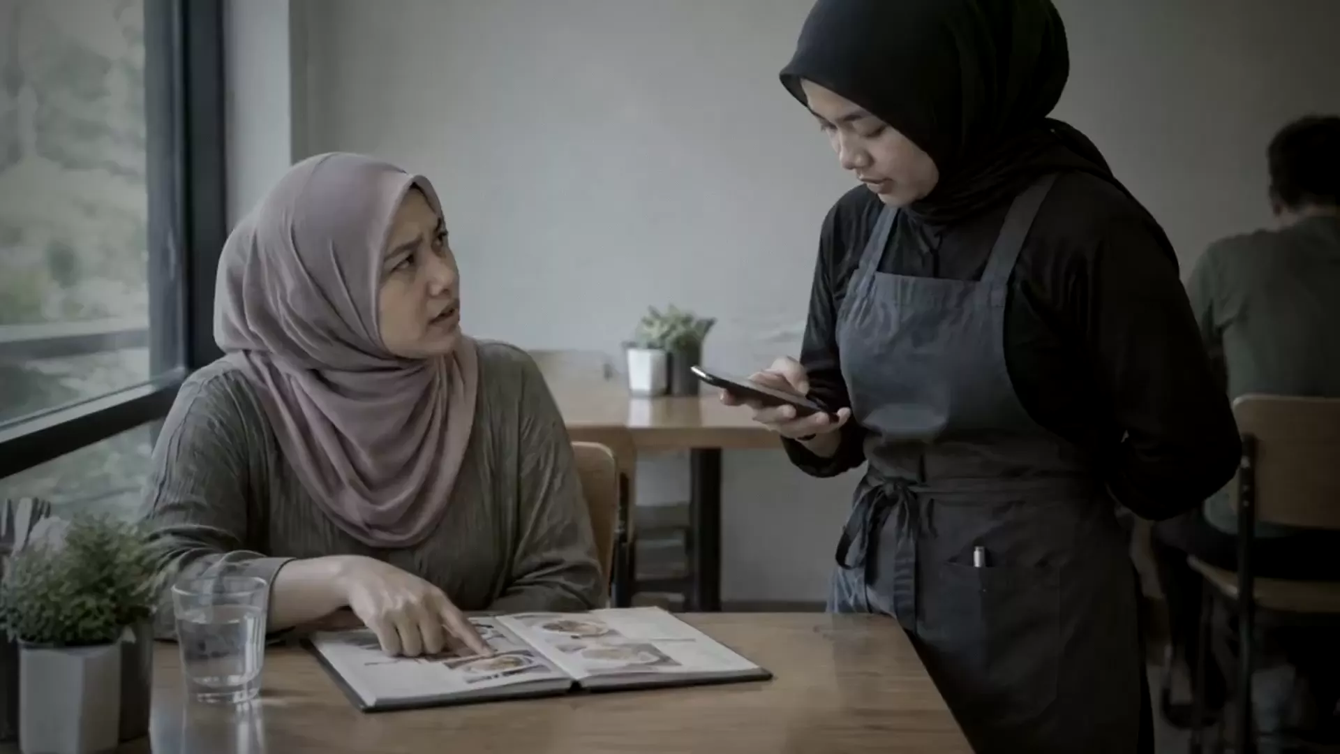 A server checking the allergen card on her phone while a guest asks about a dish